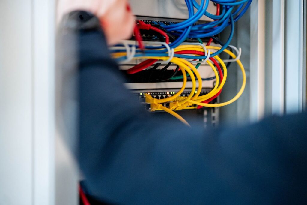 Elektriker arbeitet an Netzwerkverkabelung im Schaltschrank